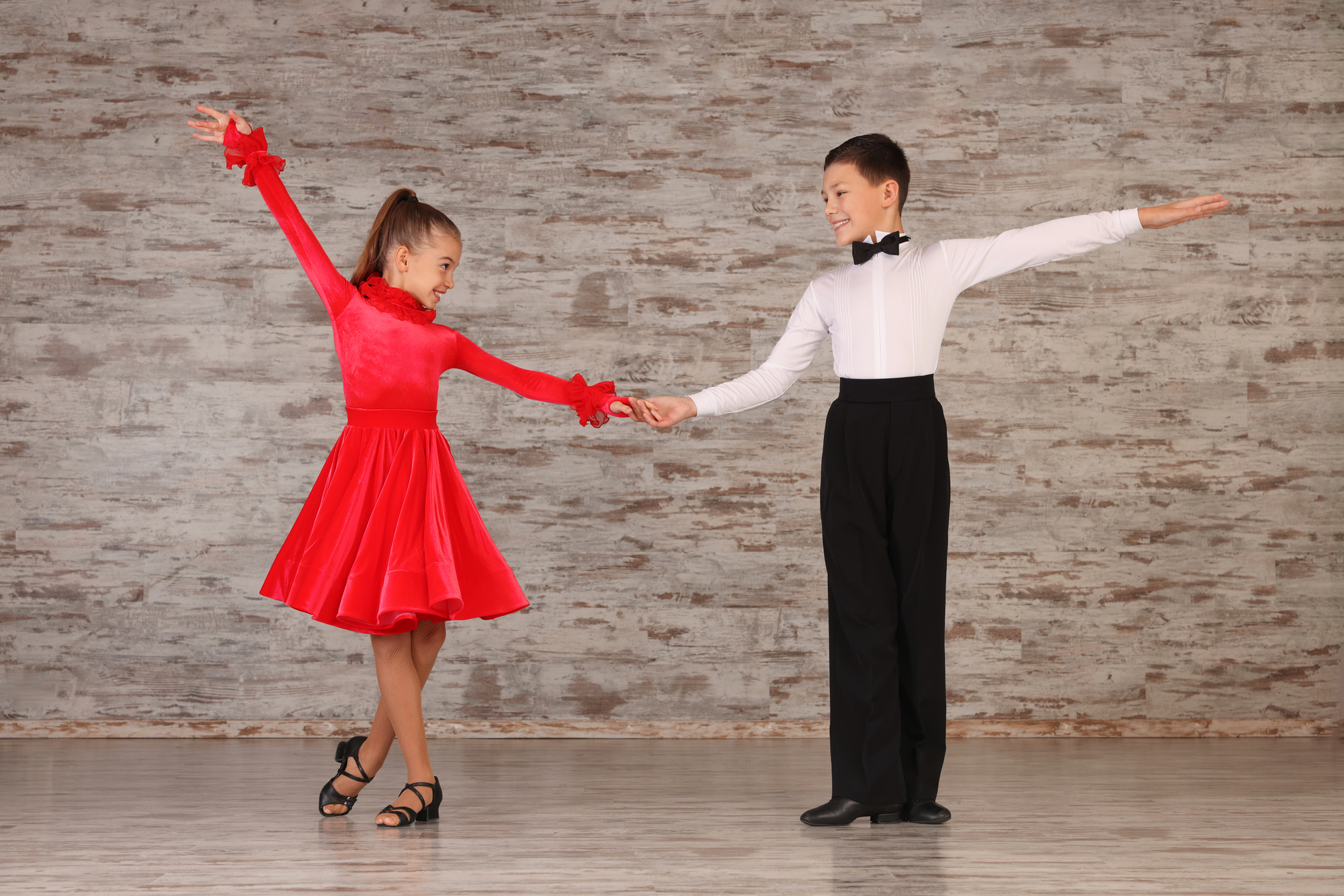 Beautifully dressed couple of kids dancing together in studio